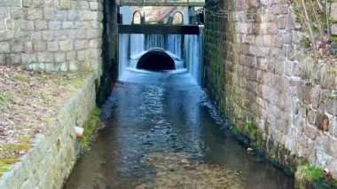 Güzel, taşlaşmış bir drenaj kanalından süzülen huzurlu ve huzurlu bir su manzarası.