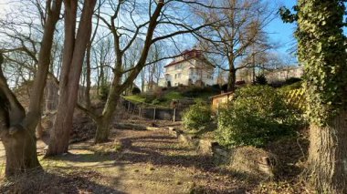 Çiçekli ağaçlar ve yeşilliklerle çevrili sevimli, küçük bir evin olduğu pitoresk bir manzara.