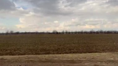 Bulutlu bir gökyüzünün altında, doğa ile ilgili projeler için mükemmel geniş bir alana sahip sakin bir kırsal alan..