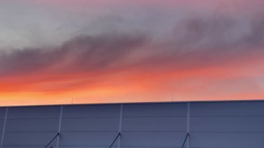 Aşağıdaki siluetli yapıya güzel bir tezat oluşturan parlak ve parlak renkler gösteren çarpıcı bir günbatımı.