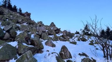 Nefes kesici ve sakin bir kış manzarası sergileniyor kayalar güzel bir şekilde masmavi gökyüzüne karşı karla kaplanıyor.