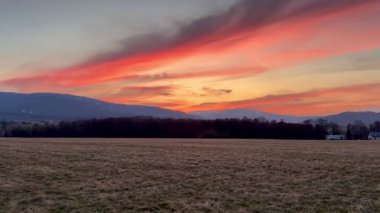 Nefes kesen bir gün batımı dingin bir manzaranın üzerindeki canlı renklerle genişleyen gökyüzünü canlı bir şekilde aydınlatıyor.