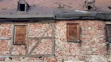 Ahşap panjurlar ve kırsal bir çatı sergilenen eskimiş tuğla bir duvar.