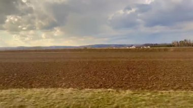 Ekilmiş tarlaların nefes kesici manzarası karamsar bulutların altında uzanır, doğanın saf güzelliğini gözler önüne serer.