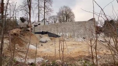 Bu resim, sadece tek bir taş duvarın sağlam kaldığı terk edilmiş bir inşaat alanını gösteriyor.