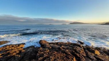 Güneşin doğuşunda kayalık kıyılara çarpan dalgaların nefes kesici görüntüsü, doğanın huzurunu yakalıyor..