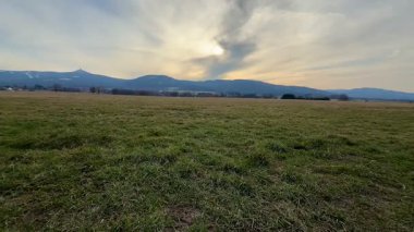 Muhteşem dağlarla dolu engin ve açık bir arazinin nefes kesici ve çarpıcı manzarası güzel bir günbatımı gökyüzünün altında.