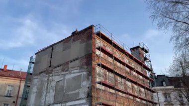 Tamamlanmamış bir bina duvarları ve inşaat iskelesi görünüyor.