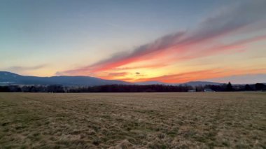 Nefes kesici ve çarpıcı bir günbatımı engin açık araziler ve uzak dağlar üzerine canlı ve parlak renkler döküyor.