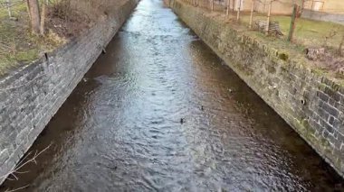 Taş duvarları olan büyüleyici bir kanaldan zarif bir şekilde akan berrak ve huzurlu bir su manzarası.