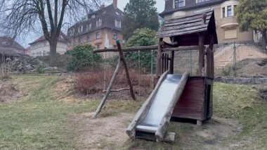 Tahta kaydıraklı ve salıncaklı güzel bir oyun parkının huzurlu manzarası, neşeli çocuklar için mükemmel.