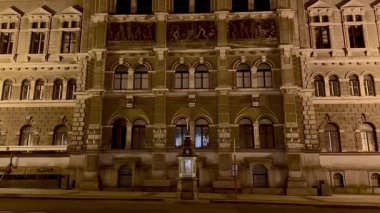 Güzelce aydınlatılmış tarihi bir bina zarif bir şekilde mimari detaylarını gece gözler önüne seriyor.