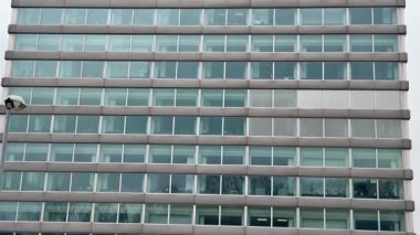 Bu çağdaş ofis binasında, sayısız büyük pencereyle vurgulanmış çarpıcı, parlak cam bir cephe sergileniyor.