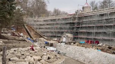 İskele, kazı ve çeşitli yapı malzemeleriyle bir inşaat alanını gösteren detaylı bir manzara.