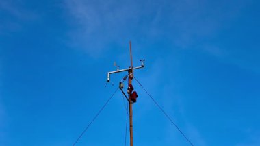 Çok yetenekli bir teknisyen parlak mavi gökyüzüne karşı bir elektrik direği üzerinde gerekli bakım işlerini yapar.