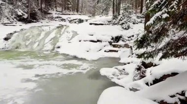 Donmuş bir şelaleyi gözler önüne seren güzel, sakin bir kış manzarası. Etrafı karla kaplı ağaçlarla çevrili.