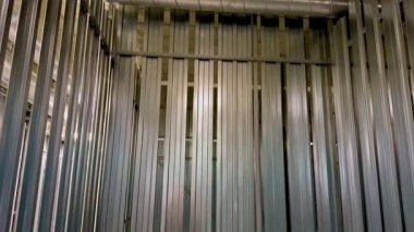 Dikey metal levhalar içeren boş bir metal depolama kabını gösteren bir iç görünüm