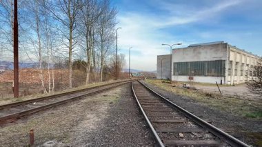 Terk edilmiş ve aşırı gelişmiş bir demiryolu hattının güzel sakin manzarası eski bir sanayi binasının yanında.