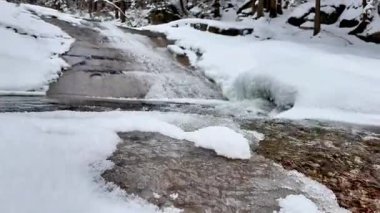 Donmuş bir derenin huzurlu ve resimsel manzarası. Güzel, el değmemiş, karla kaplı bir araziyle çevrili.