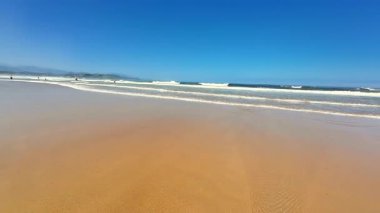 Resmedilmeye değer ve sakin bir sahil sahnesi. Nazik dalgalar, kristal berrak gökyüzü ve yumuşak altın kum.