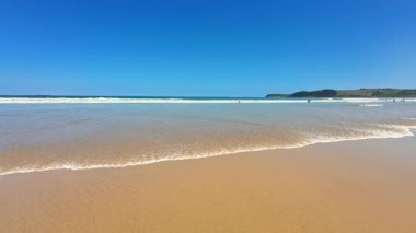 Yumuşak kum, berrak turkuaz su ve inanılmaz derecede canlı mavi gökyüzü içeren güzel ve pitoresk bir sahil sahnesi.