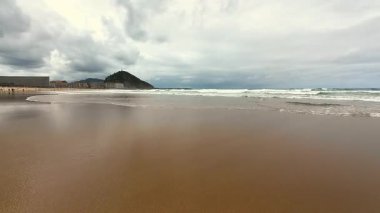 Sakin bir sahil sahnesi, yumuşak dalgalar ve kasvetli bir gökyüzü, rahatlamak ve günlük hayattan kaçmak için mükemmel.