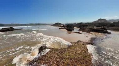 Güzel kayalar, çarpan dalgalar ve açık gökyüzü olan manzaralı bir sahil manzarası, sahil anılarını yakalamak için mükemmel.