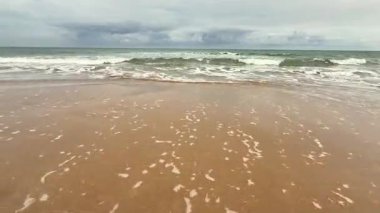 Yumuşak dalgalar ve yumuşak kumlar sergilenen güzel sakin bir sahil sahnesi, çeşitli rahatlama temaları için ideal.