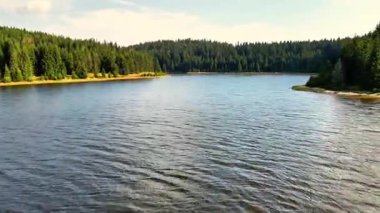 Canlı yeşilliklerle süslenmiş, suyun yüzeyine güzel yansıyan pitoresk bir göl.