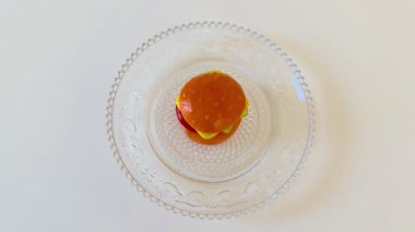Lezzetli bir mini burger dekoratif cam tabakta servis edilir. Gurme sunumları için idealdir.