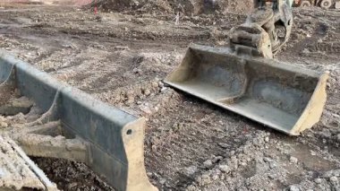 Etkin bir inşaat sahasında çeşitli kazı araçlarının sergilendiği ağır makineler gözlemlenebilir