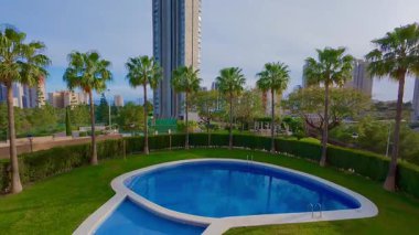 Nefes kesici bir havuz manzarası verimli yeşillik tarafından çerçevelenir ve modern mimari tasarımlarla tamamlanır.