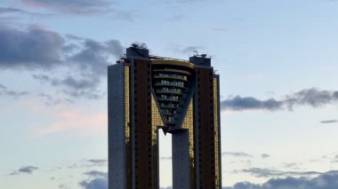 Çarpıcı ve etkileyici bir modern gökdelen tasarımı nefes kesen bir günbatımı arka planıyla güzel bir şekilde vurgulanır.