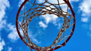 Göz kamaştırıcı bir manzara, berrak mavi gökyüzü ve kabarık beyaz bulutlar karşısında canlı bir basketbol potası yakalıyor.