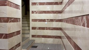 Bu modern merdiven zarif mermer duvar panelleri ve parlak mimari elementlerle şık bir tasarım sergiliyor.