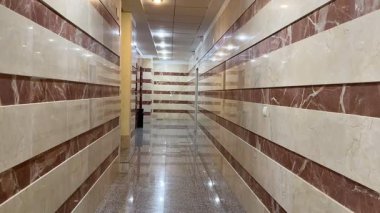 Şık mermer duvar tasarımlarının çeşitli ticari alanlar için mükemmel olduğu gösterişli ve modern bir koridor.