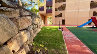 Canlı bir oyun alanı, yemyeşil otlar, rahat banklar ve mükemmel bir atmosfer yaratan bir yerleşim alanı.