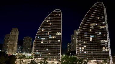 Aydınlatılmış kulelerin, açık bir gece gökyüzüne karşı modern mimarinin sergilendiği çarpıcı manzarasına hayran olun.