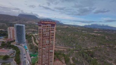 Yeşillik ve dağlarla donatılmış modern konut binalarını gösteren hava görüntüleri..