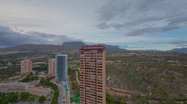 Görkemli dağları ve yemyeşil manzarası olan yüksek şehir binalarını gösteren hava görüntüleri.