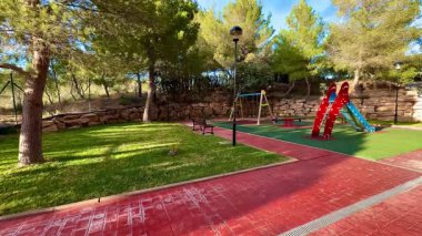 Oyun parkında, bereketli ağaçlarla çevrili sakin bir park ortamına yerleştirilmiş canlı ve çekici ekipmanlar yer alıyor.