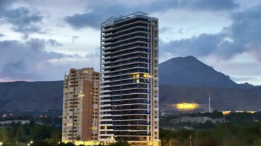 Güzel bir şehir manzarası, özellikle alacakaranlıkta, dağlara karşı çağdaş binalar sergiliyor ve manzaraları büyüleyici hale getiriyor.