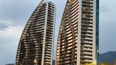 Benzersiz kıvrımlı gökdelenler alacakaranlıkta aydınlanır, modern tasarım ve olağanüstü mimari sergilenir.