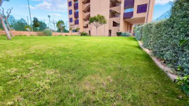 Modern bir apartmanın yanındaki yeşil çimlerin güzel ve güzel manzarası.