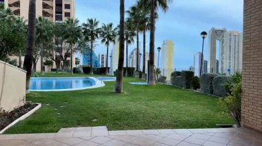 Çağdaş gökdelenlerle birlikte yemyeşil alanları da barındıran nefes kesici ve nefes kesici bir havuz manzarası.