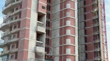 Bu resim inşaat halindeki çok katlı bir binayı, yapı iskelesi ve görünür tuğla işçiliğini gösteriyor.