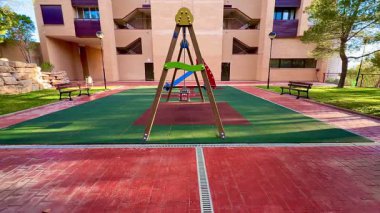 Canlı ve renkli bir oyun alanında, iyi korunmuş bir salıncak tüm çocuklar için eğlenceli ve çekici aktiviteler sağlar.