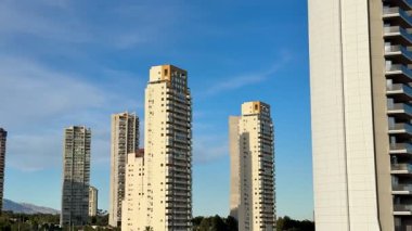 Parlak mavi gökyüzüne karşı görkemli bir şekilde duran parlak, yüksek binaların nefes kesici ve çarpıcı manzarası.