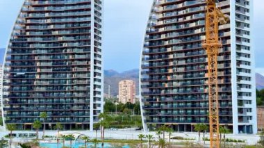 Şu anda yapım aşamasında olan parlak kulelerin büyüleyici görüntüsü, canlı kentsel ortama karşı bir vinç içeriyor.