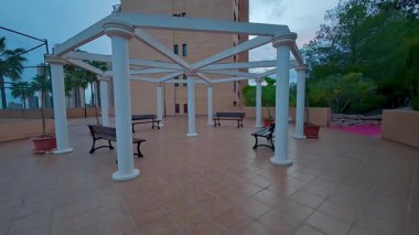 Birden fazla sıranın ve yüksek palmiye ağaçlarının bulunduğu sakin, açık bir pavyon, onu rahatlama için mükemmel kılıyor.